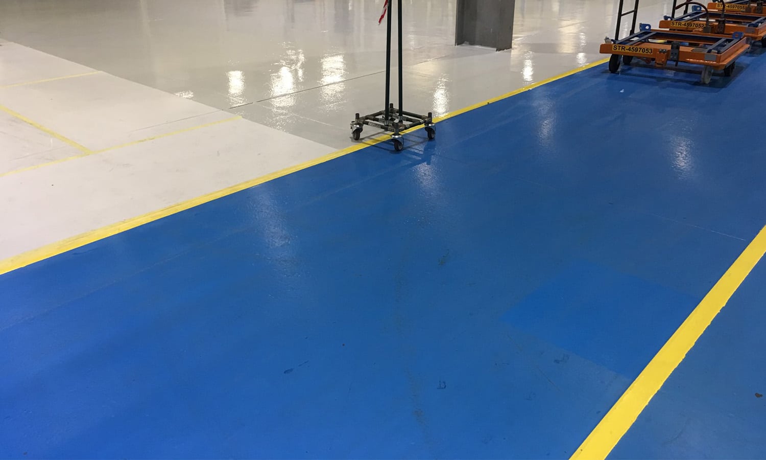 This image shows a factory floor with blue and yellow epoxy floor.
